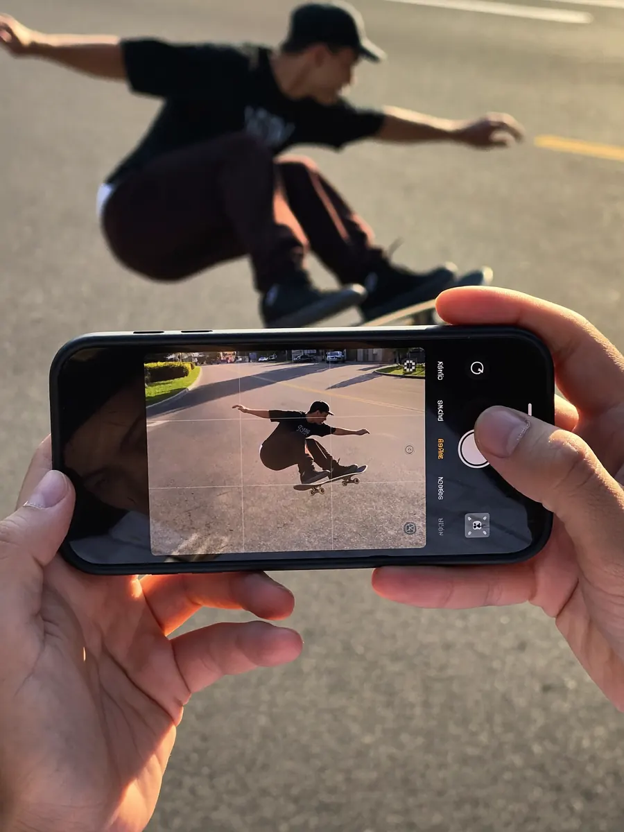 Hands filming a skateboard trick on a phone